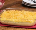 Travessa de vidro com um fricassê de franco dourado do forno e coberto por batata palha.