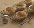 Muffins de banana com canela fofinhos, e polvilhados com açúcar e canela, servidos em formas individuais.