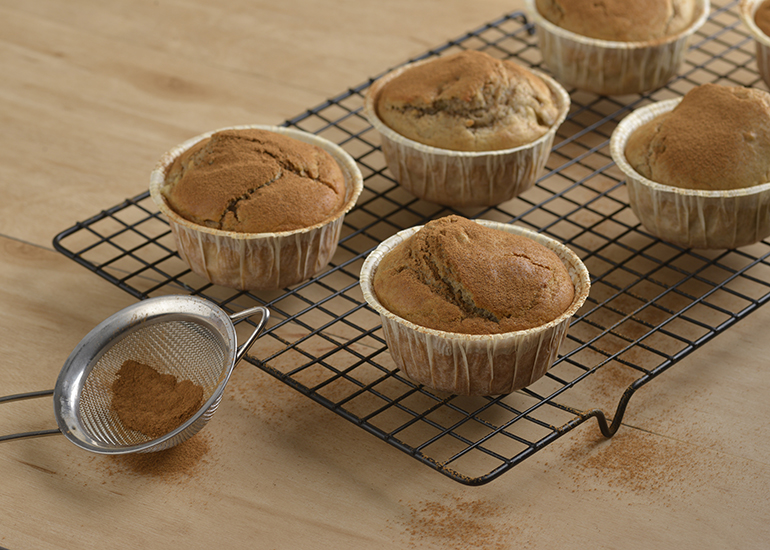 Muffins de banana com canela fofinhos, e polvilhados com açúcar e canela, servidos em formas individuais.