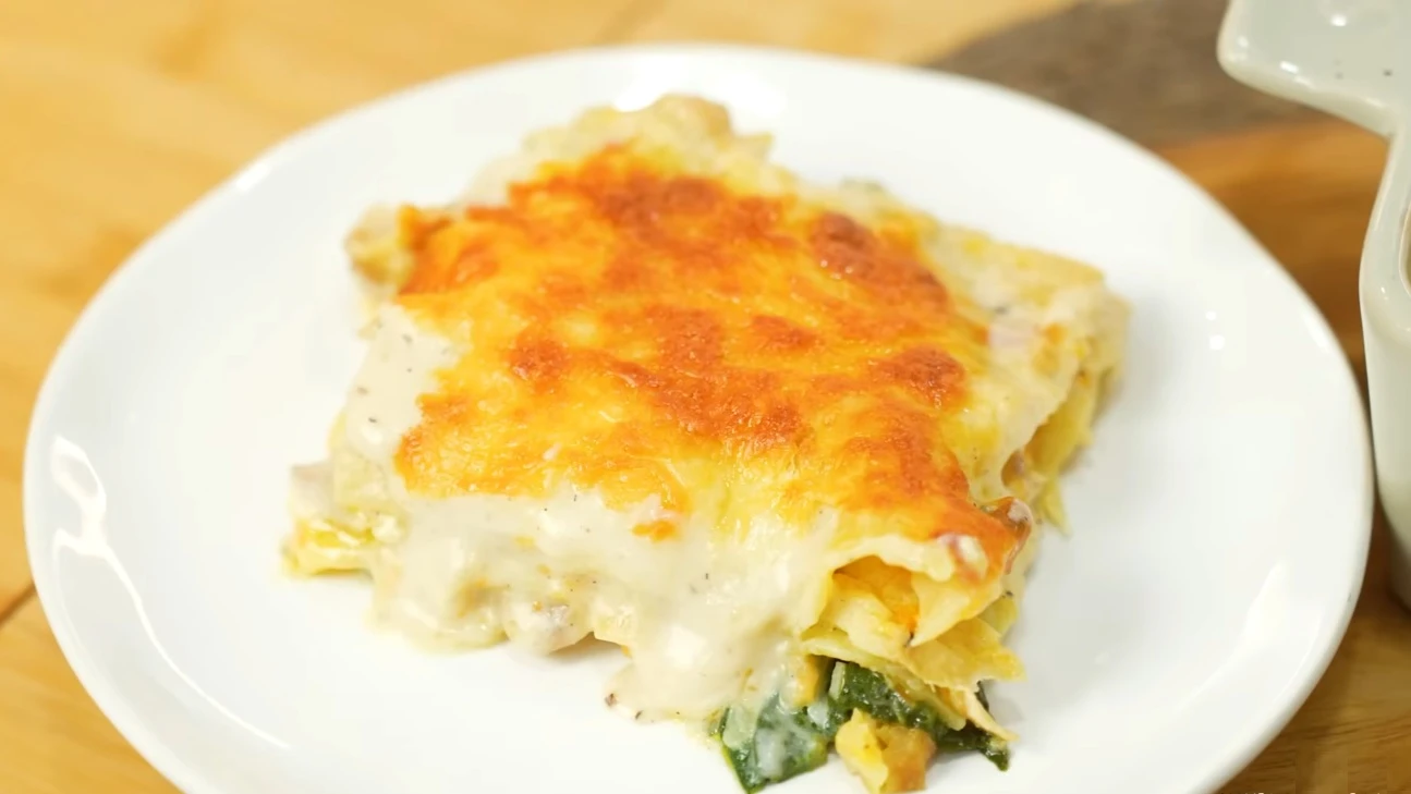 Lasanha de bacalhau servida em prato branco.